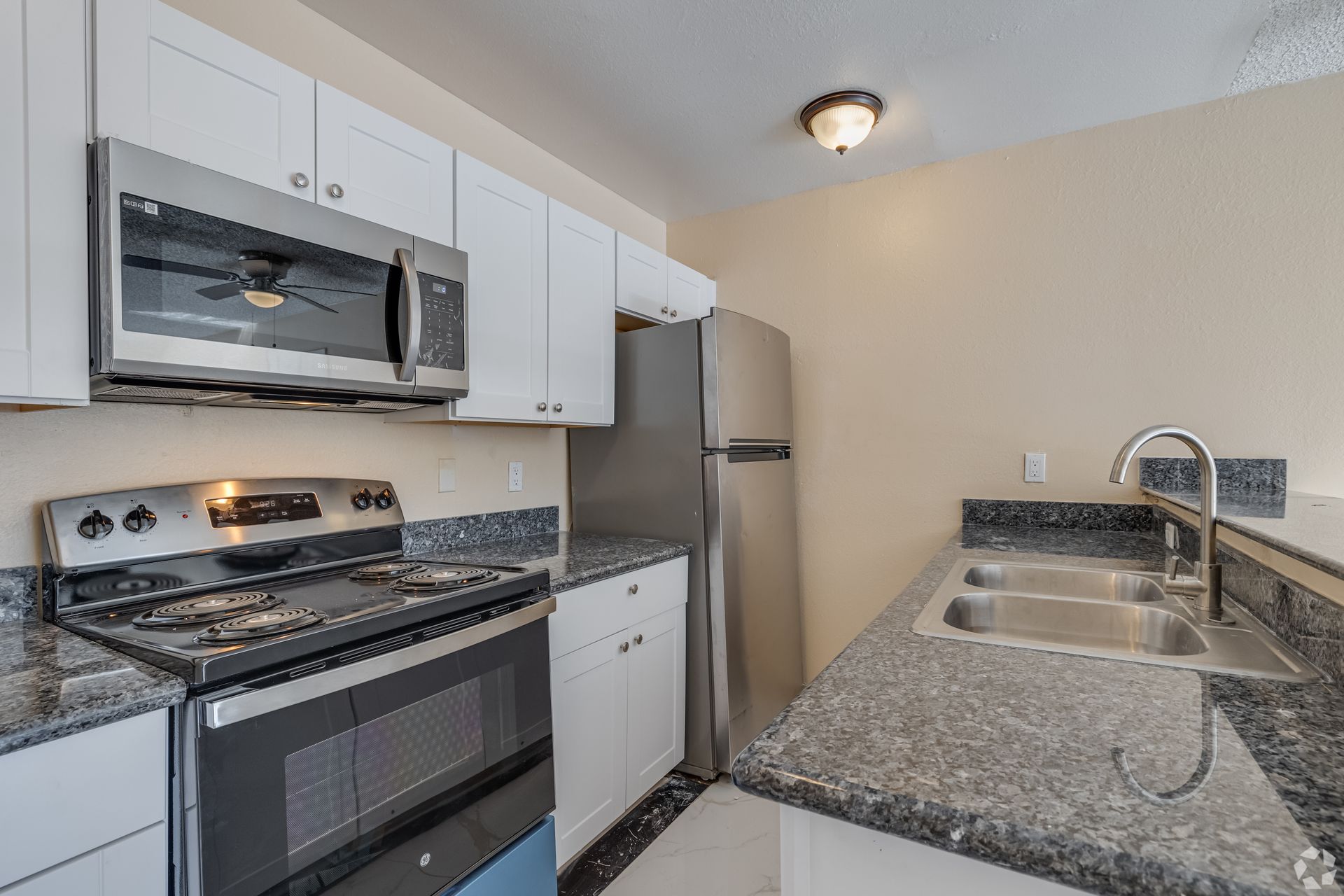 Kitchen with stainless steel appliances, white cabinets, and dark countertops.