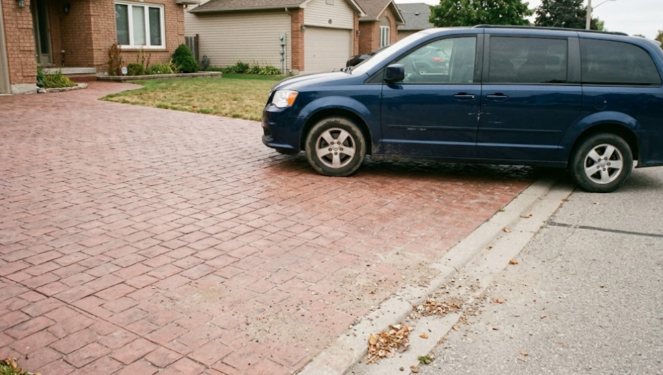 A blue minivan is parked on a red patterned decorative concrete driveway in Frederick, MD.