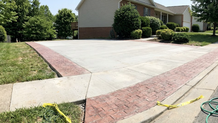 A smooth and durable concrete driveway with decorative brick borders installed in Frederick MD.