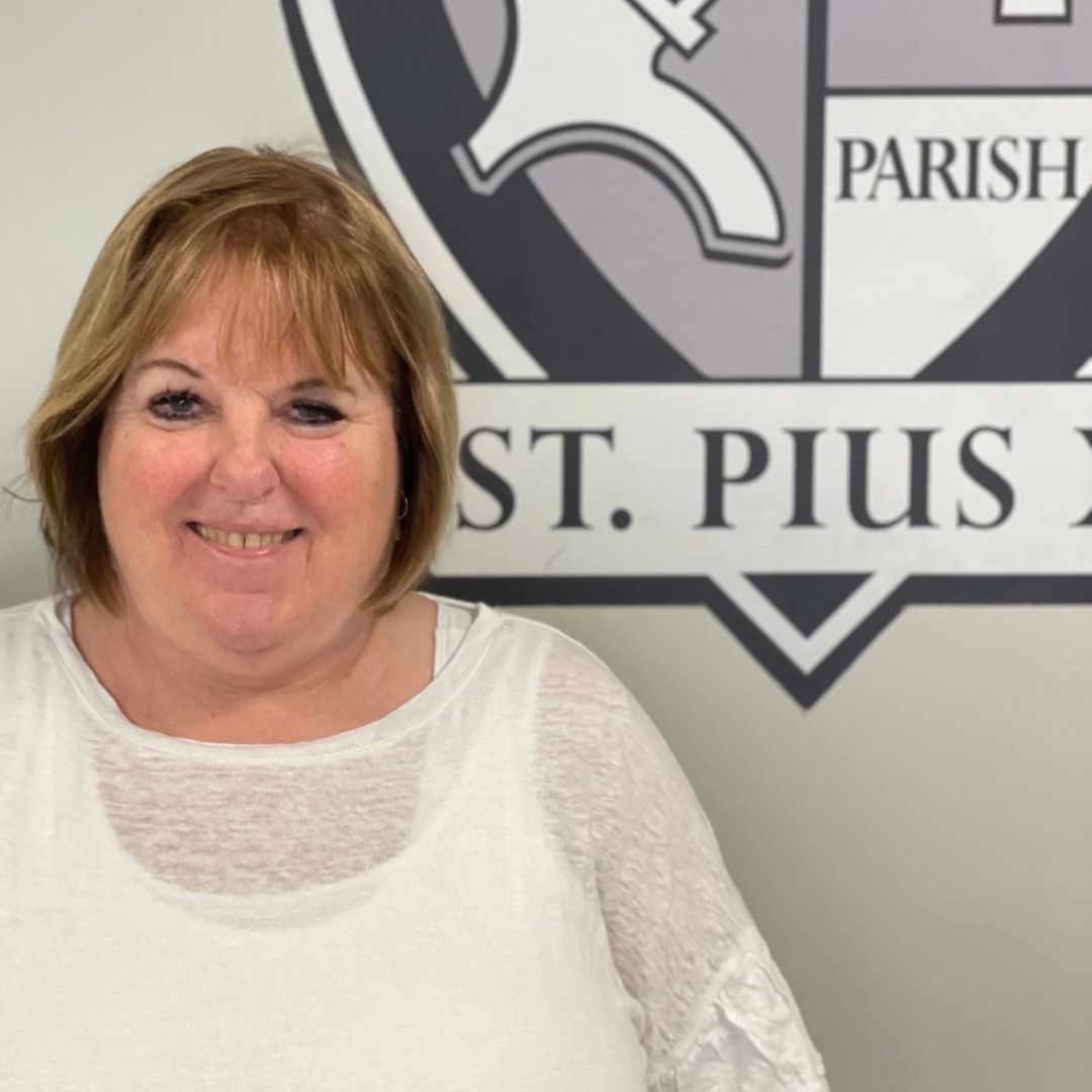 A woman stands in front of a sign that says st. pius