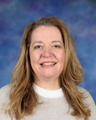 A woman in a black shirt is smiling in front of a building that says st.