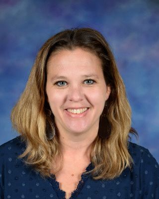 A woman in a purple shirt is smiling for the camera.