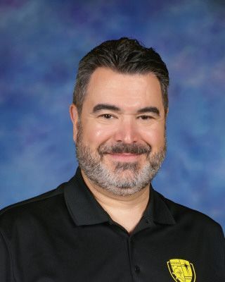 A man with a beard is wearing a black shirt that says mr. romane.