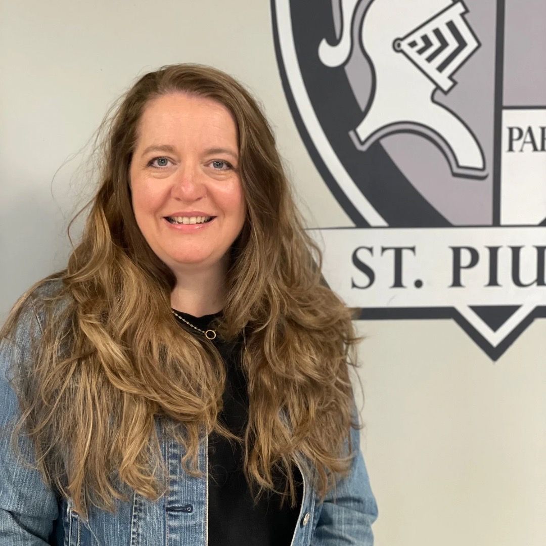 A woman is smiling in front of a sign that says st. piu