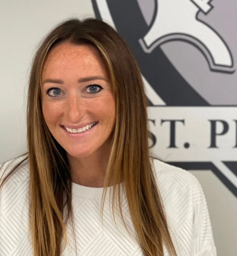 A woman is smiling in front of a sign that says st. peter.