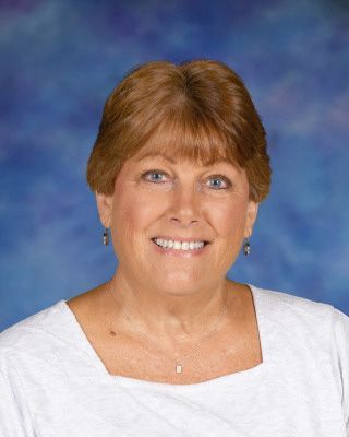 A woman in a blue shirt is standing in front of a brick building.