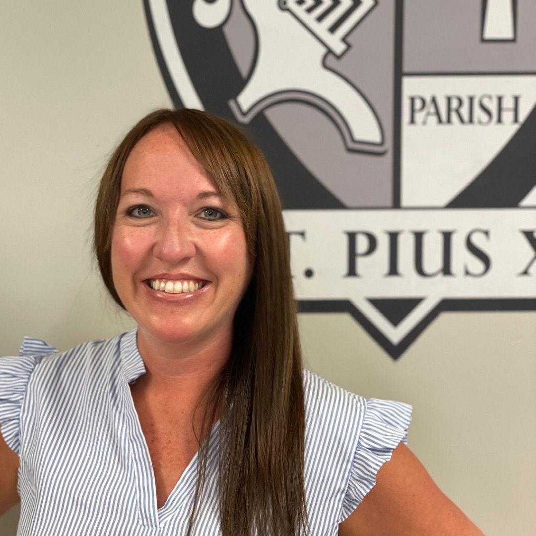 A woman smiles in front of a parish crest