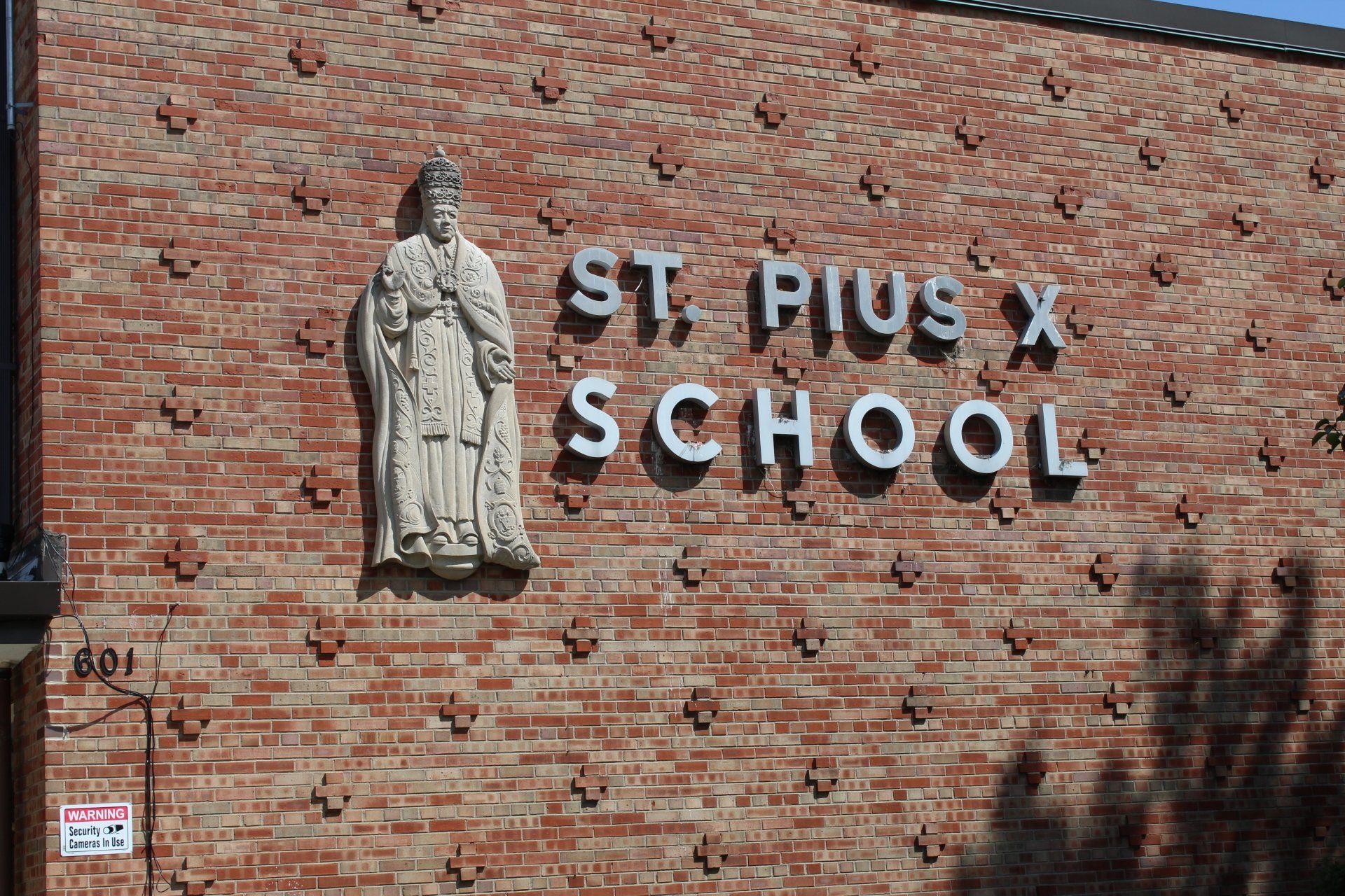 A statue of a man is on the side of a brick building.