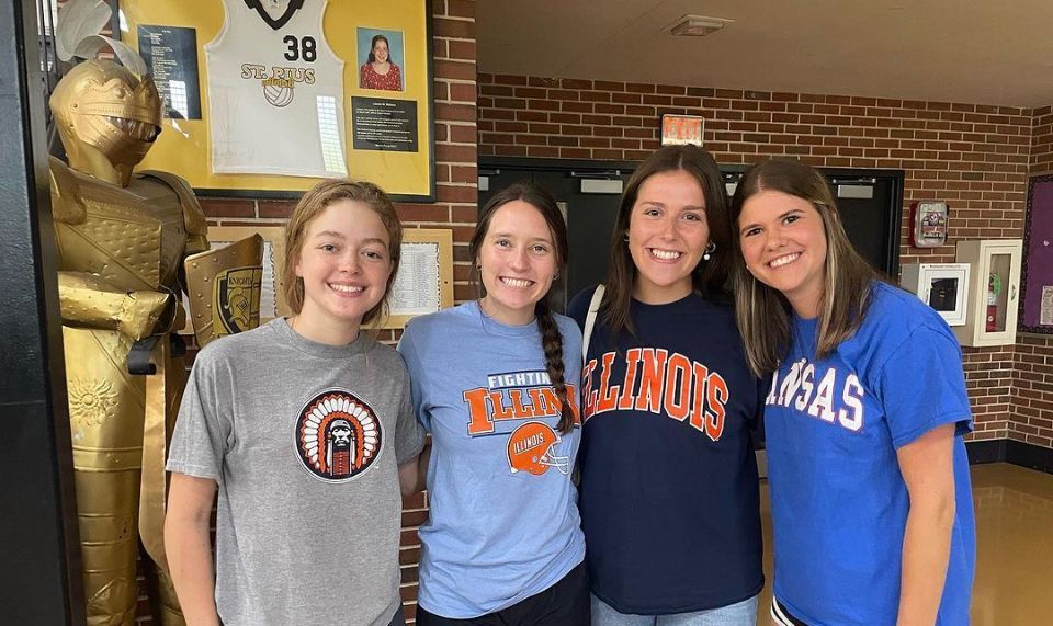 A group of young women are posing for a picture in a hallway.