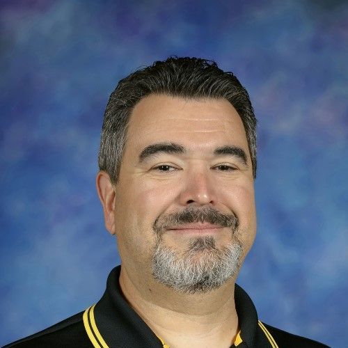 A man with a beard and mustache is smiling for the camera