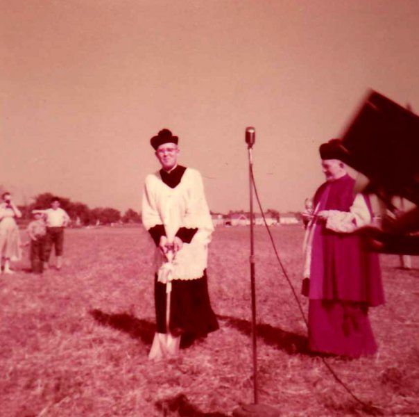 A man in a white robe is standing in a field next to a microphone