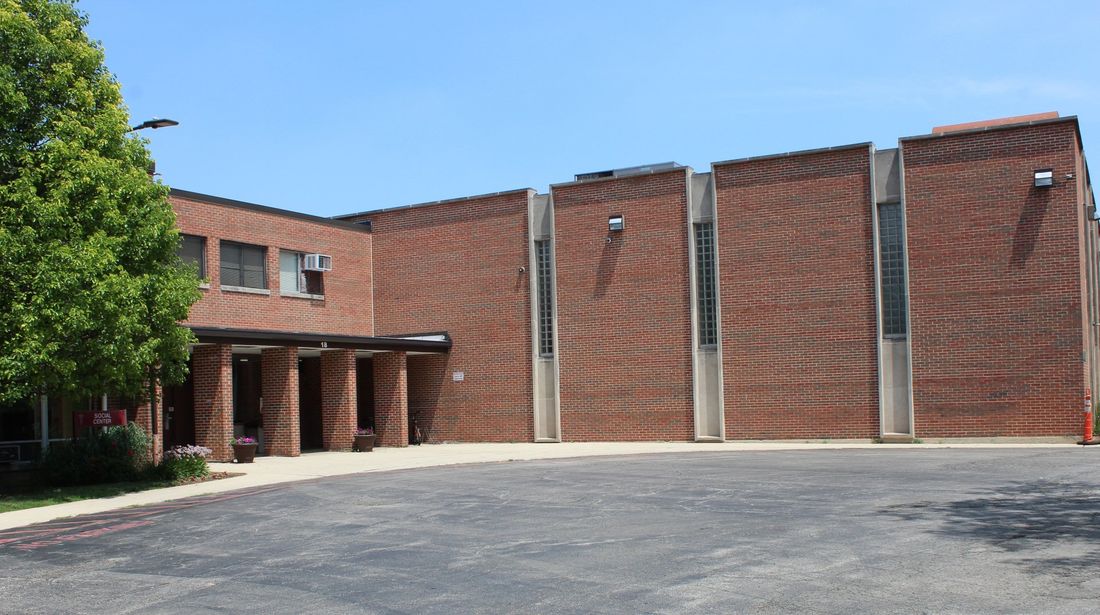 A large brick building with a parking lot in front of it.