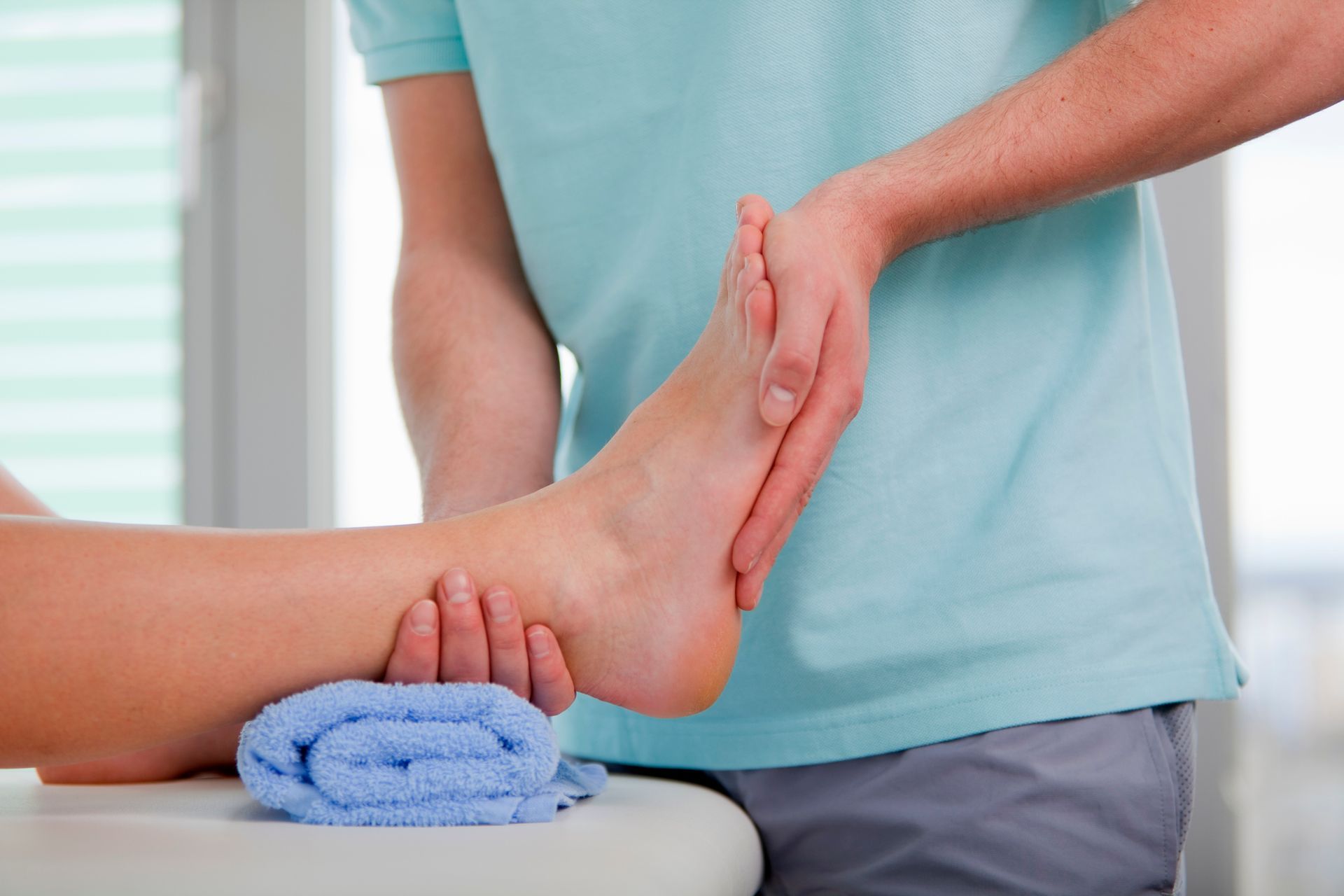 Woman receiving hot stone massage at a spa; masseuse placing warm stone on her back.