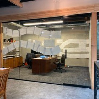 A room with a desk and chair in it and a glass wall.
