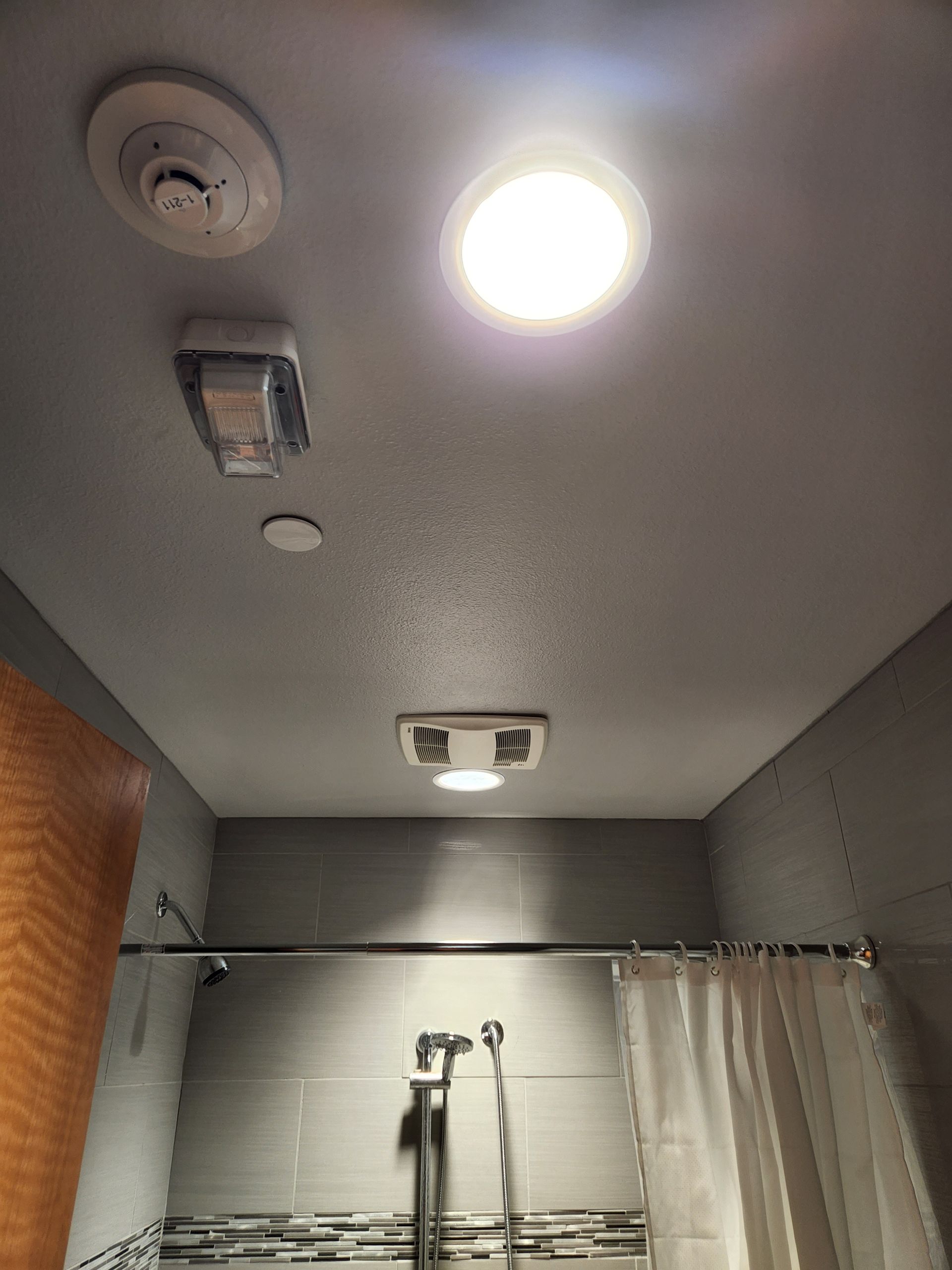 A bathroom with a shower and a ceiling light.