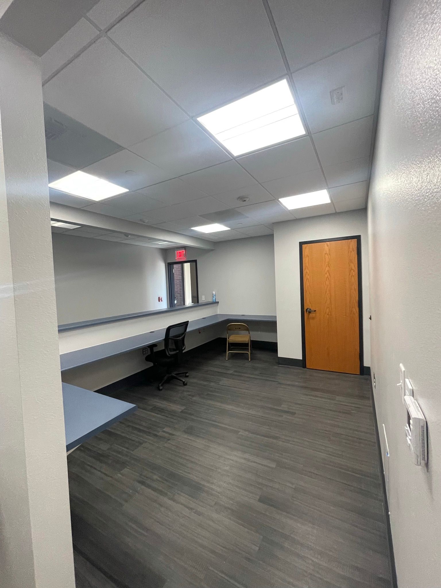 A large empty room with a wooden door and a desk.