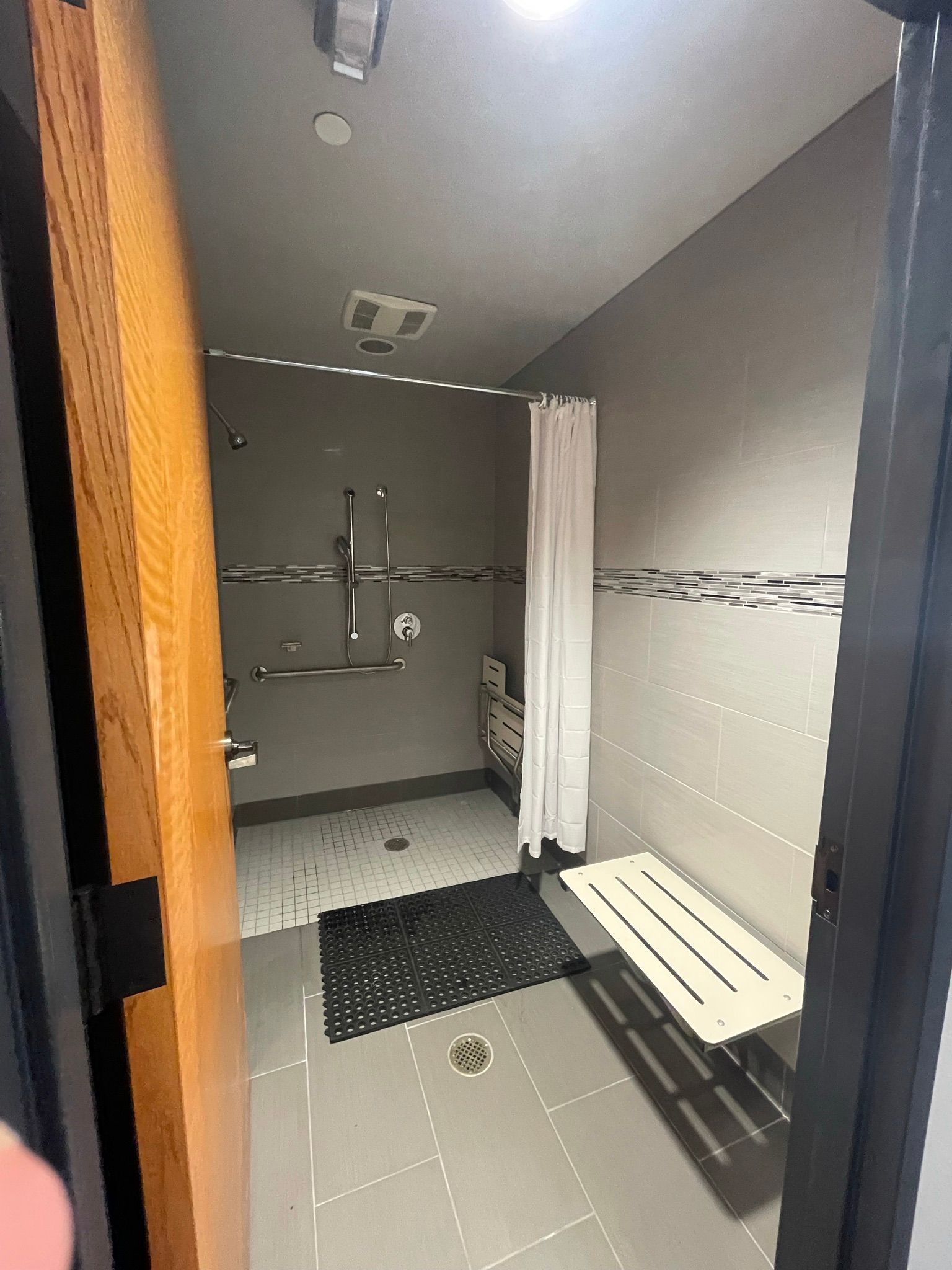 A bathroom with a shower stall and a bench.