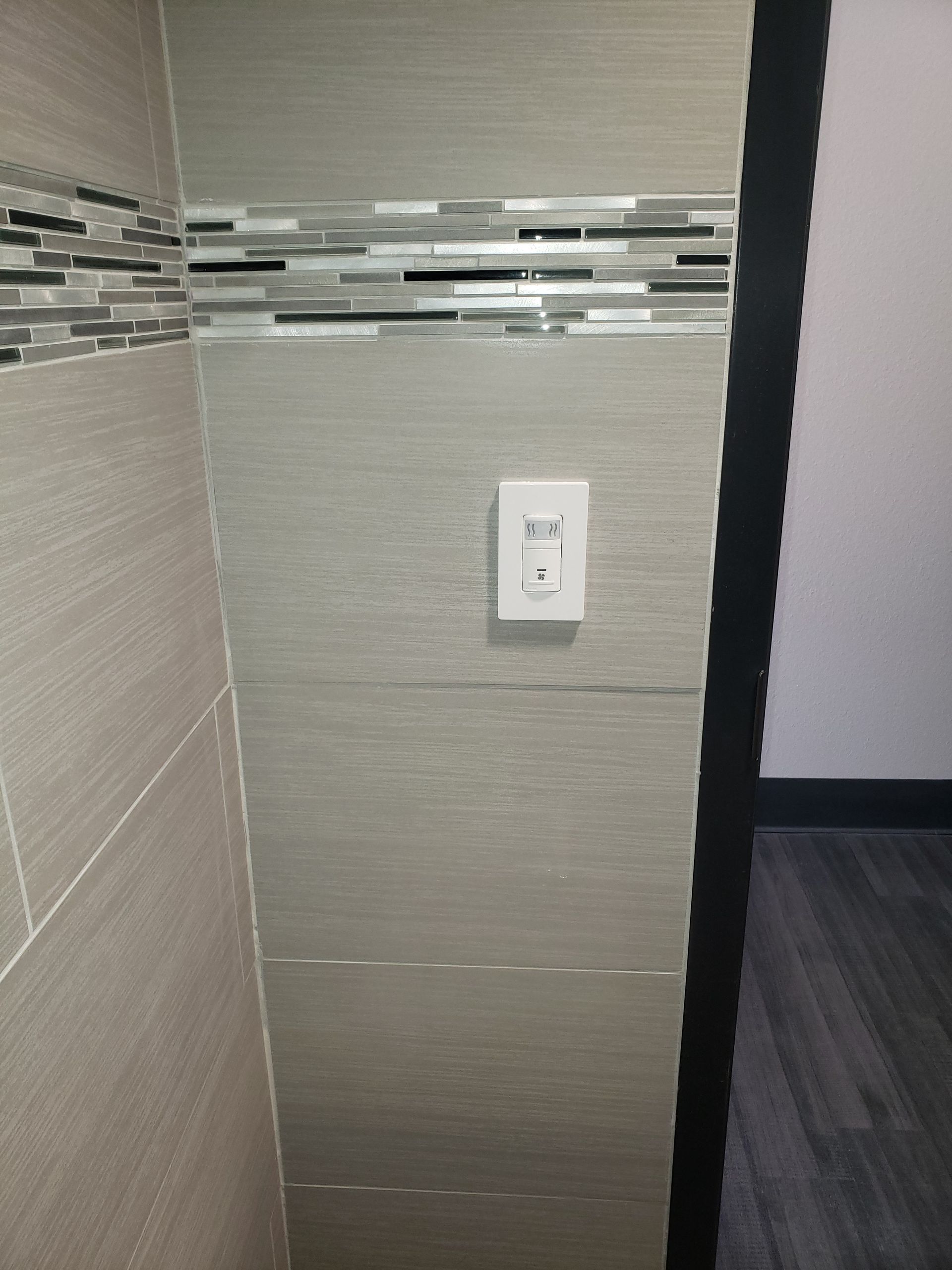 A bathroom with a light switch on the wall.
