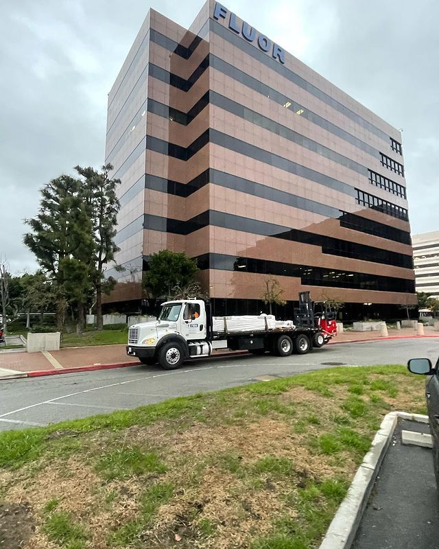 A truck is parked in front of a large building that says fluor