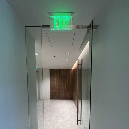 A hallway with a green exit sign on the ceiling.