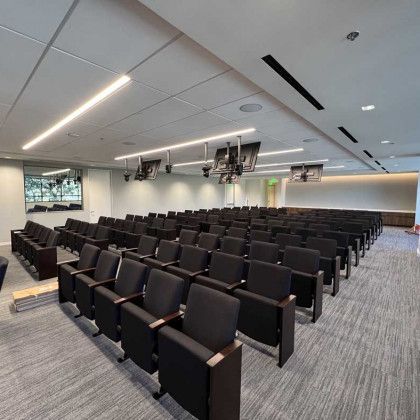 A large auditorium filled with rows of black chairs