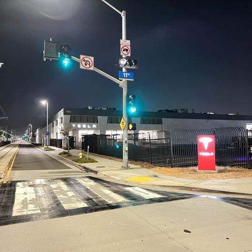 A street at night with a tesla sign in the foreground