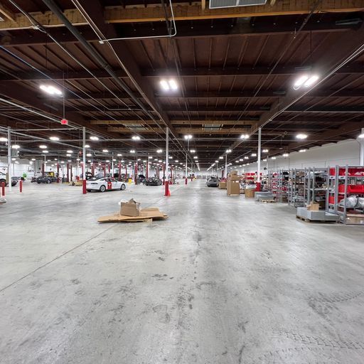 A large warehouse with a lot of cars parked in it