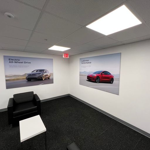 A room with two pictures of cars on the wall.