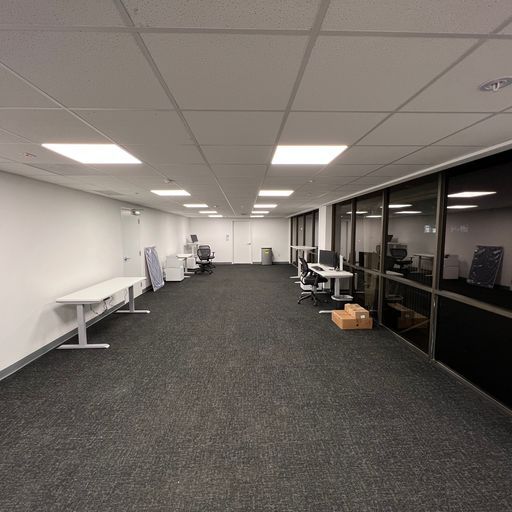 An empty office with a lot of windows and tables and chairs.