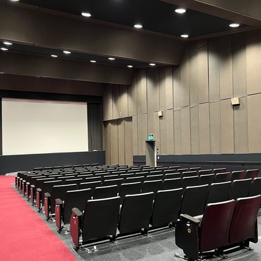 A large auditorium with rows of black seats and a large screen.