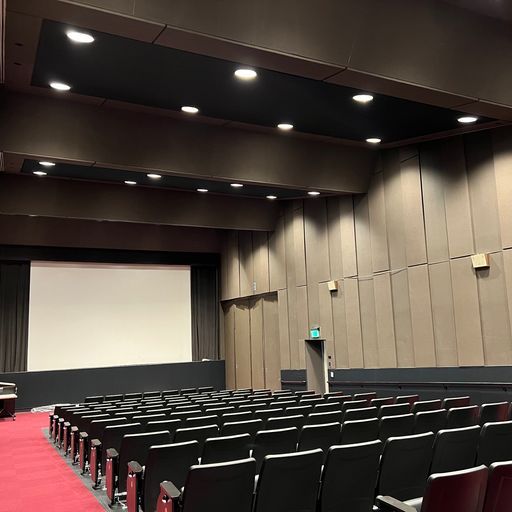 An auditorium with rows of seats and a large screen