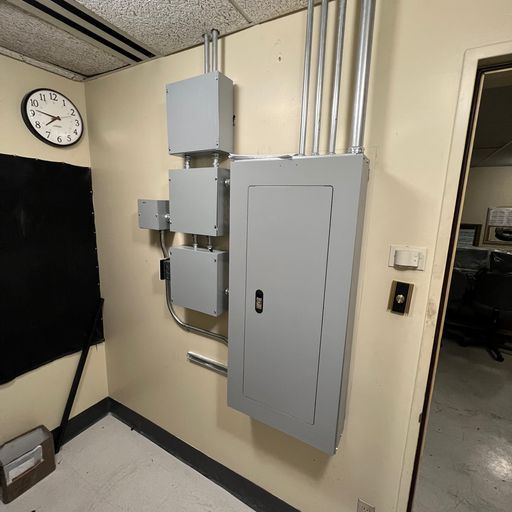 A room with a clock on the wall and a gray box on the wall