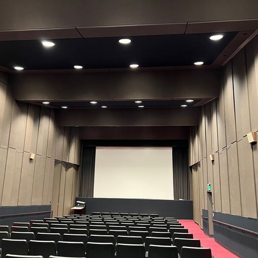 An auditorium with rows of seats and a large screen