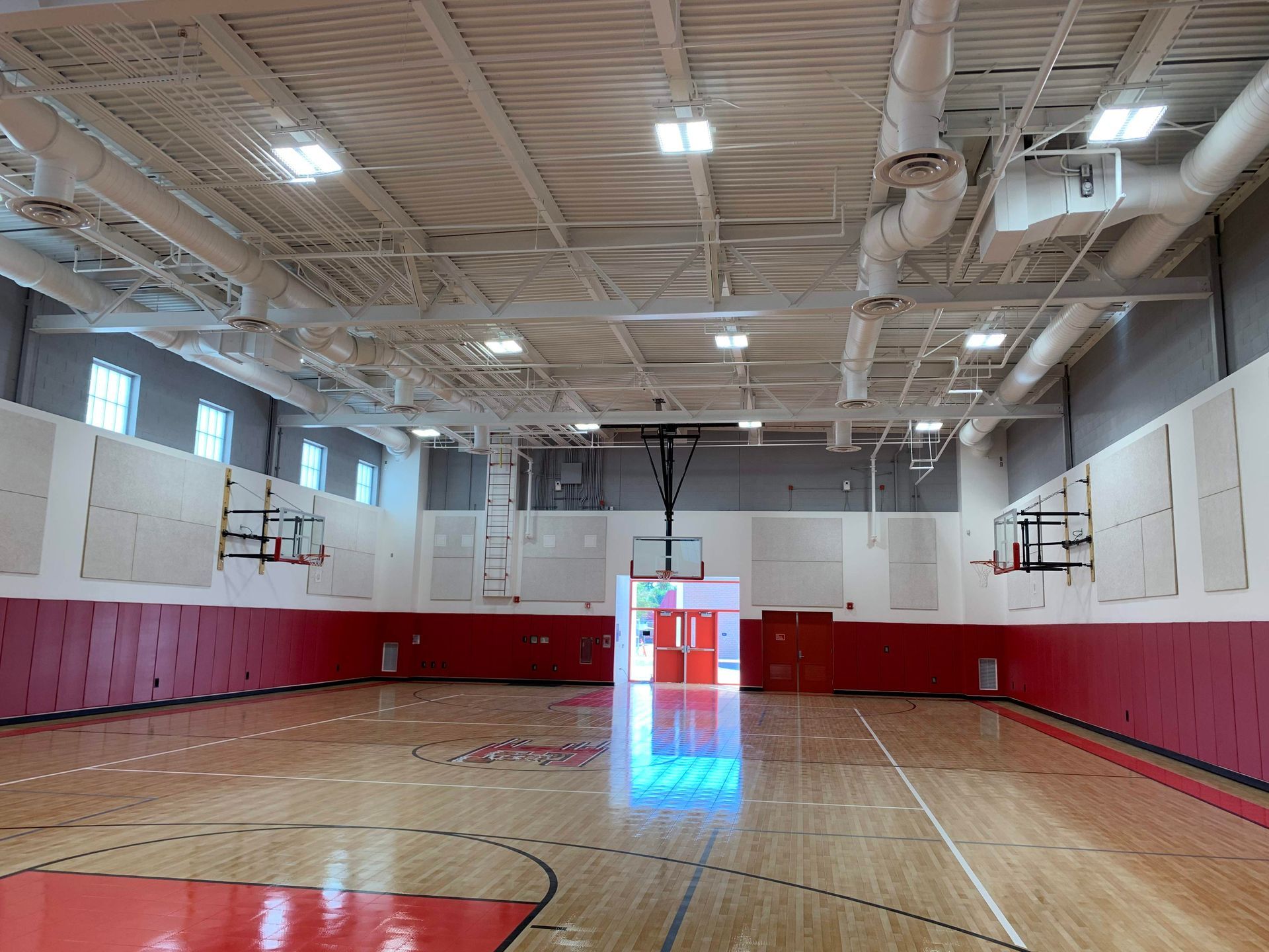 An empty basketball court in a gym with red and white walls.
