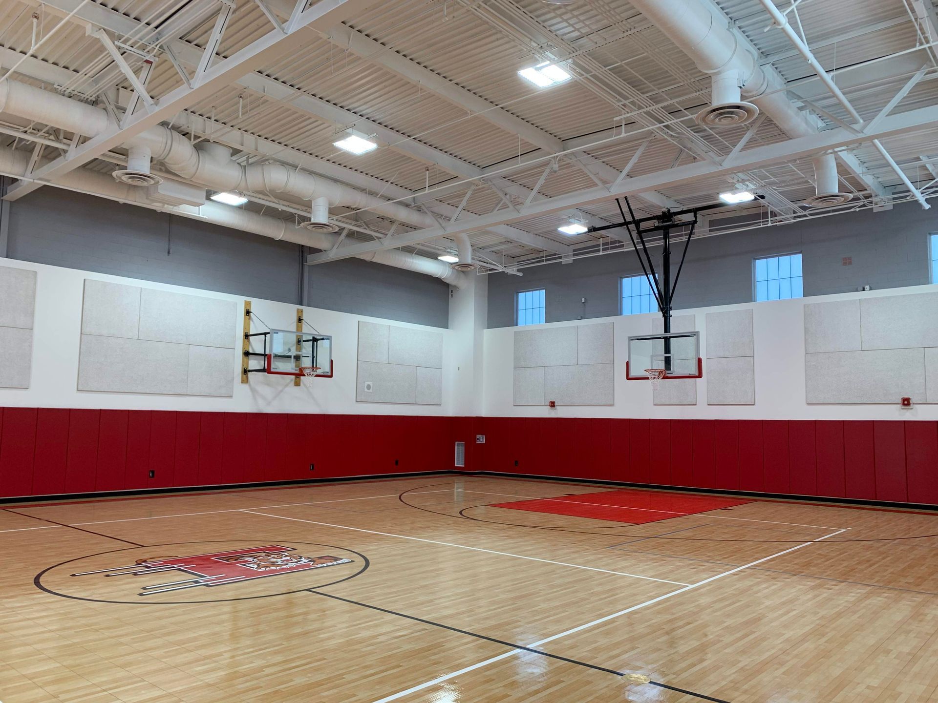 A large indoor basketball court with a wooden floor and a basketball hoop.