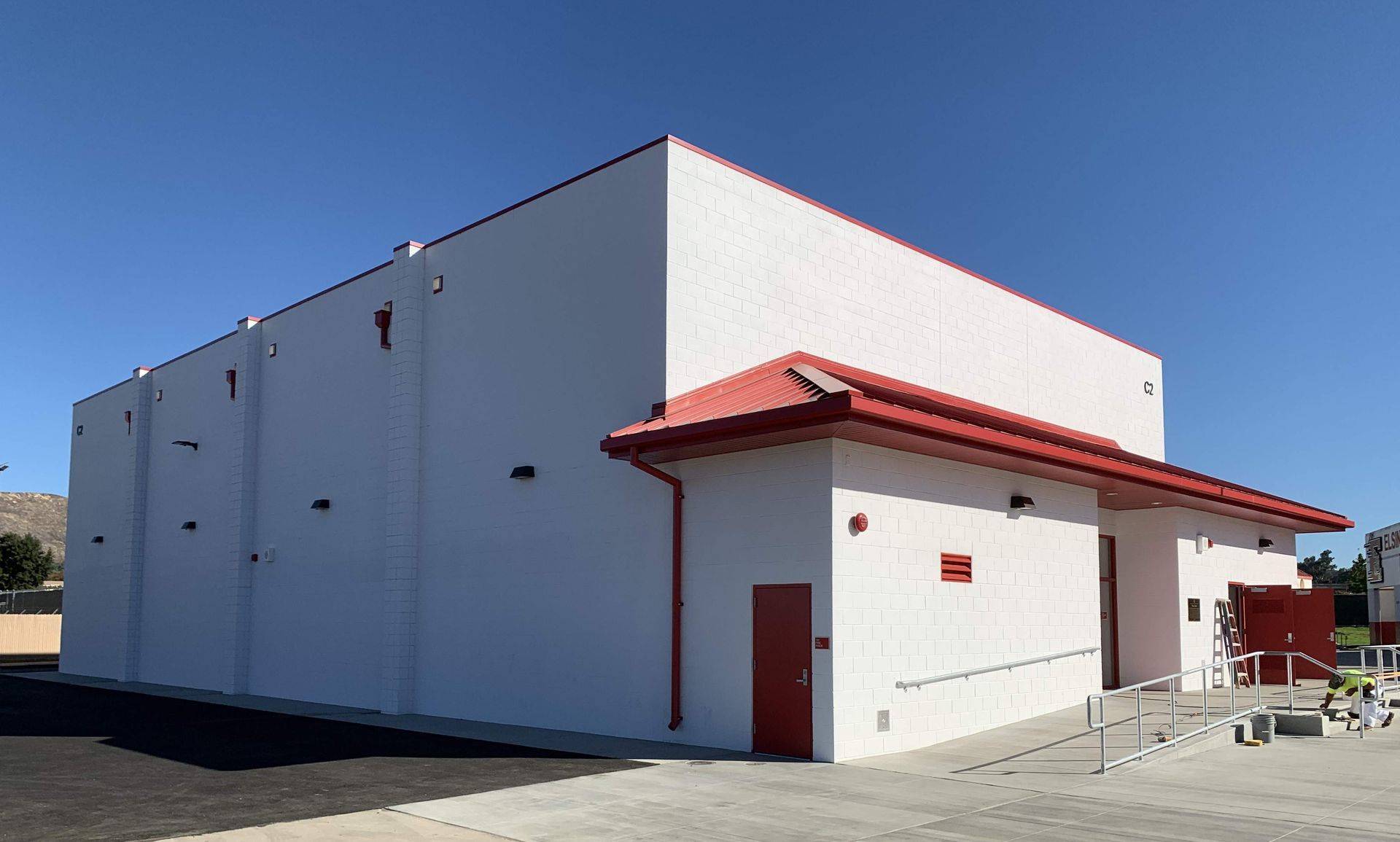 A white building with a red roof and a red door