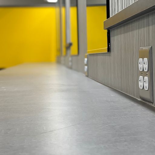 A hallway with a yellow wall and electrical outlets on the wall.