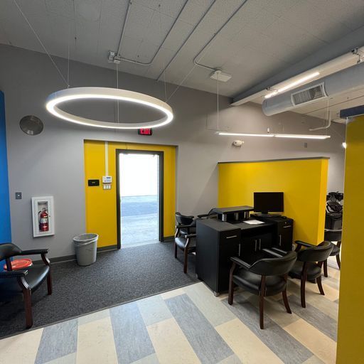 A waiting room with a yellow door and a circular light hanging from the ceiling.