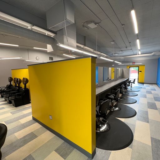 A salon with a yellow wall and black chairs