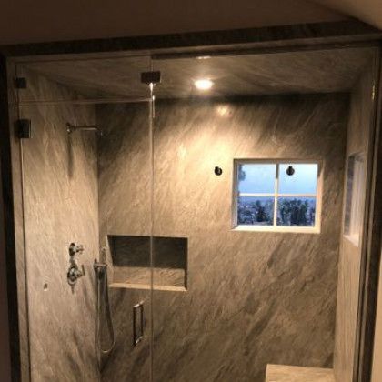 A bathroom with marble walls and a glass shower door.