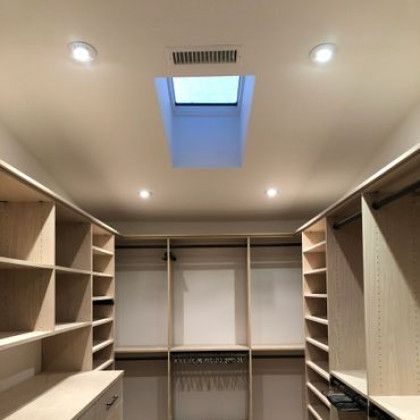 A walk in closet with lots of shelves and a skylight in the ceiling.