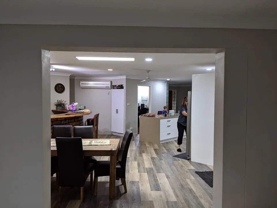 A Woman Is Standing in A Living Room Next to A Table and Chairs — MJ Render in Buderim, QLD