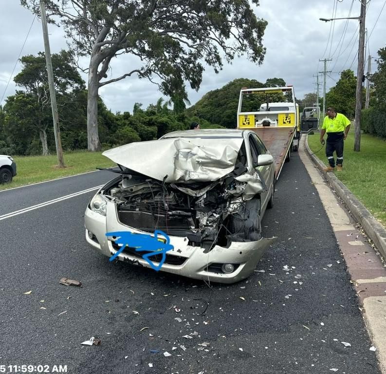 A Severely Damaged Silver Car Being Towed on a Roadside; a Tow Truck and Worker Are Present — TCC Towing Coffs Coast in Harbour, NSW