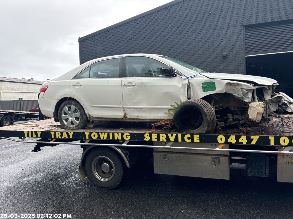 White car severely damaged on a tow truck, likely after a collision — TCC Towing Coffs Coast in Harbour, NSW