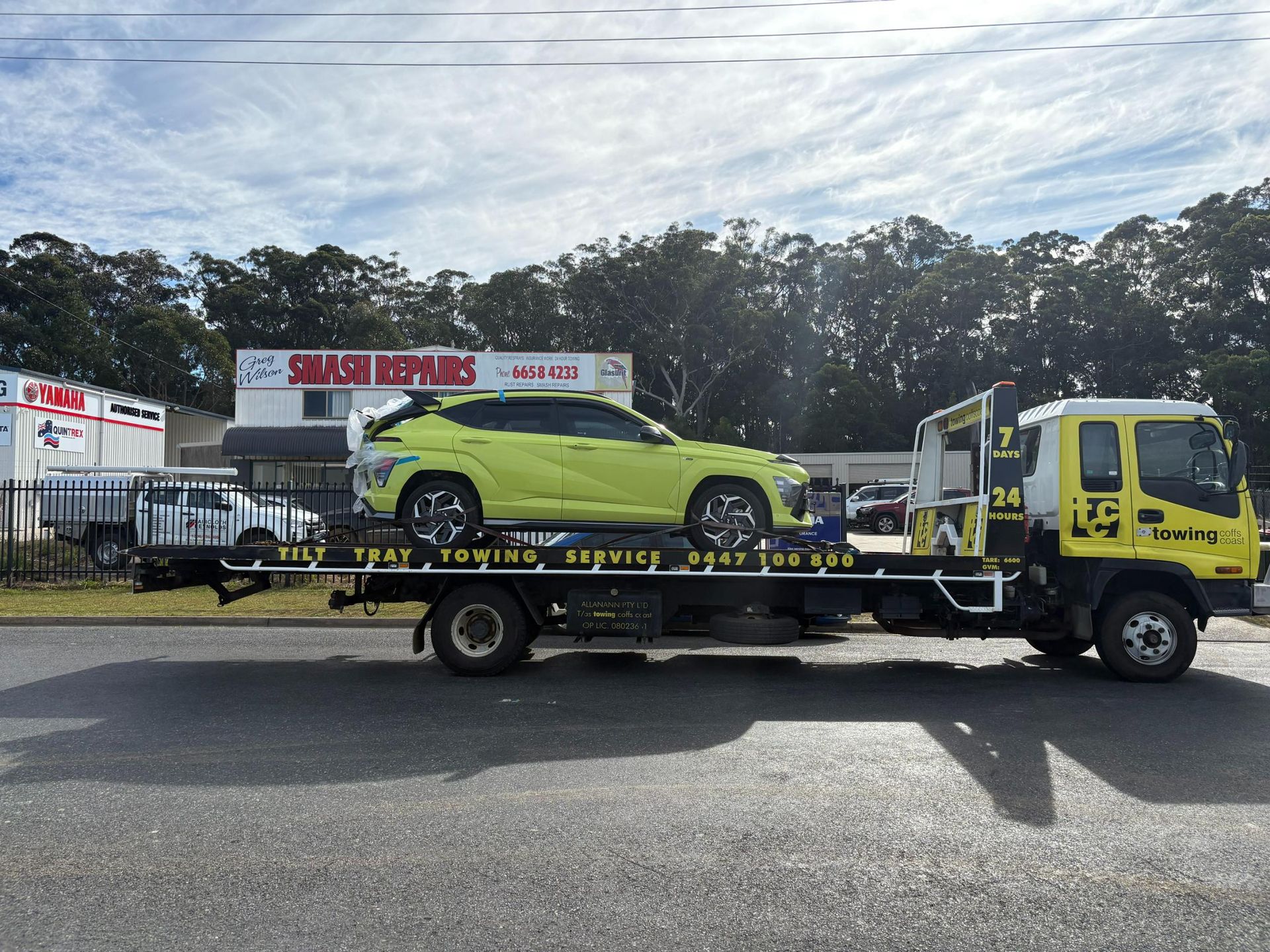 A Yellow Til Towing truck park in carrying a yellow car