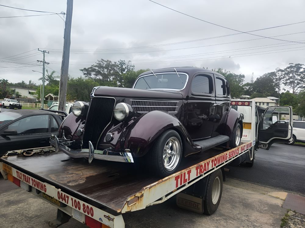 A Black Classic Car Is being towed by a tow truck — TCC Towing Coffs Coast in Harbour, NSW