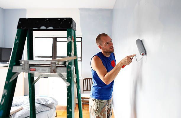 A Man Is Painting A Wall With A Paint Roller - Spring, TX - DJ's Painting