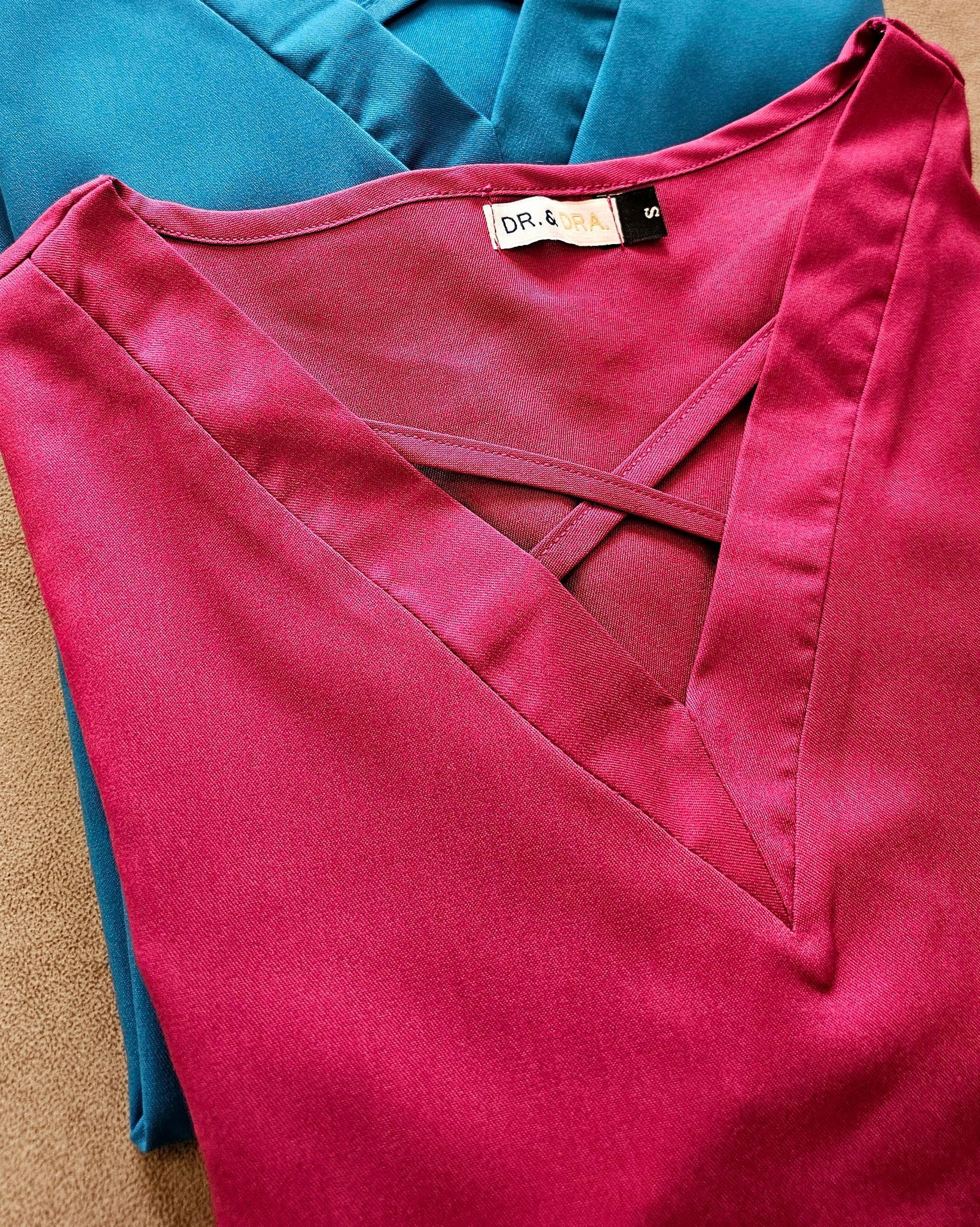 Tres mujeres sonrientes con uniformes de color magenta, posando en un consultorio médico.