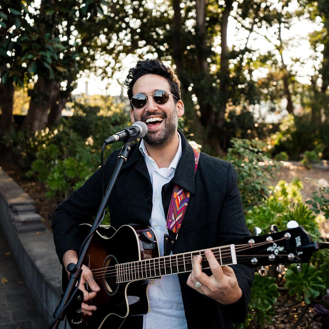 A man is singing into a microphone while holding a guitar