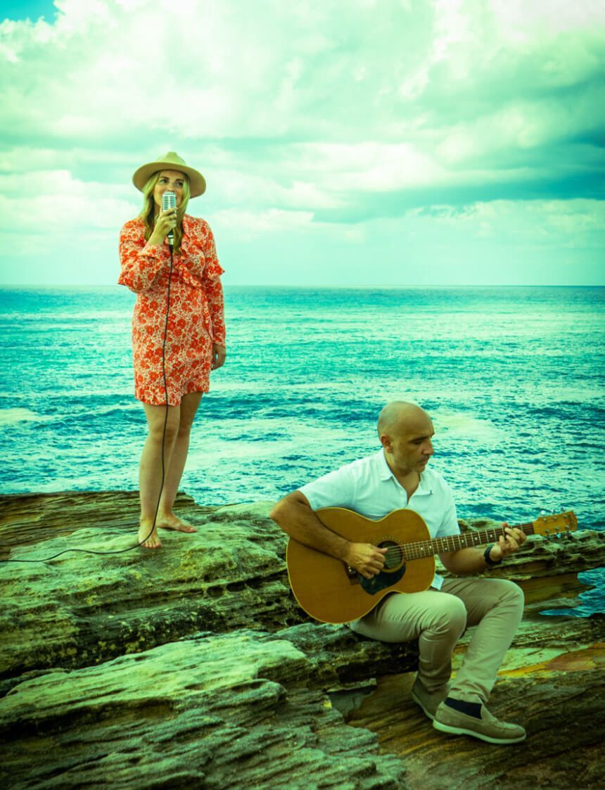 A man is playing a guitar while a woman sings into a microphone.